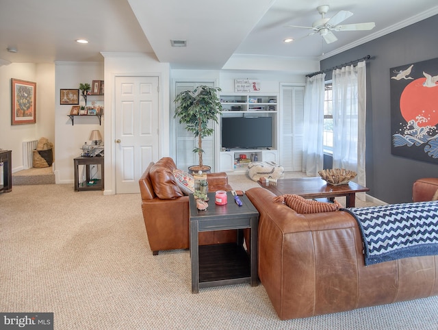 living room with visible vents, baseboards, a ceiling fan, ornamental molding, and carpet