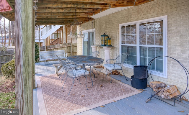 view of patio featuring outdoor dining space, fence, and a wooden deck