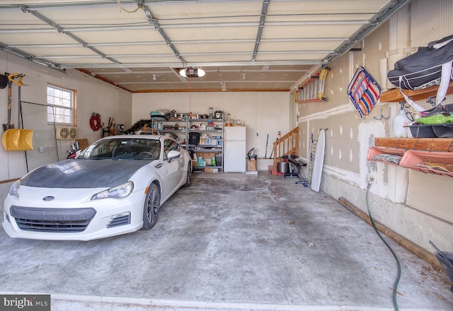 garage featuring a garage door opener and freestanding refrigerator