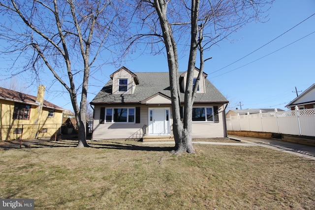 view of front facade featuring roof with shingles, a front yard, and fence