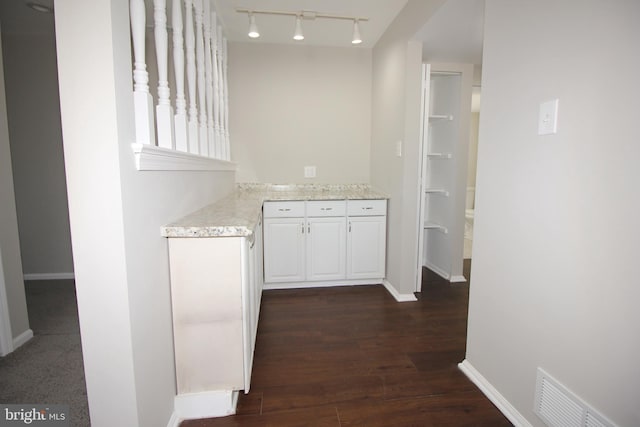 interior space with light stone counters, visible vents, baseboards, white cabinetry, and dark wood finished floors