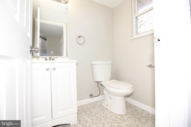 half bath featuring toilet, baseboards, and vanity