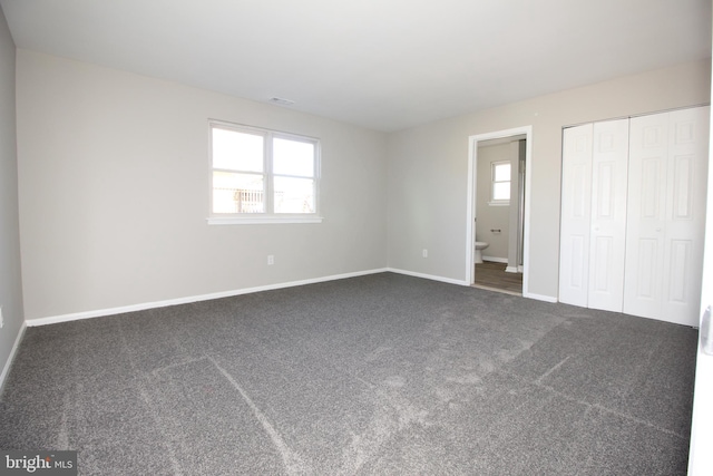 unfurnished bedroom with ensuite bathroom, a closet, carpet, and baseboards