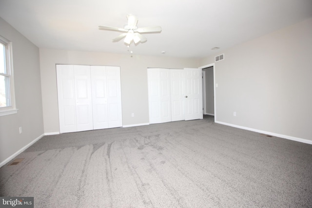 unfurnished bedroom with baseboards, visible vents, and two closets