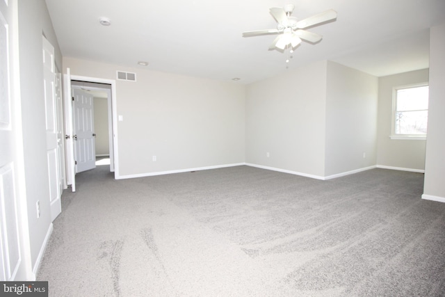 carpeted empty room featuring a ceiling fan, visible vents, and baseboards