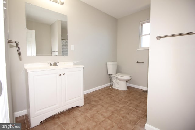 bathroom with toilet, tile patterned floors, baseboards, and vanity