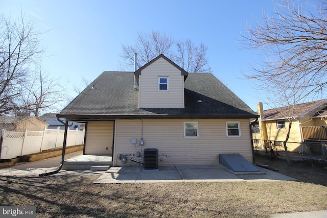 rear view of house with roof with shingles, a yard, a patio, central AC, and fence