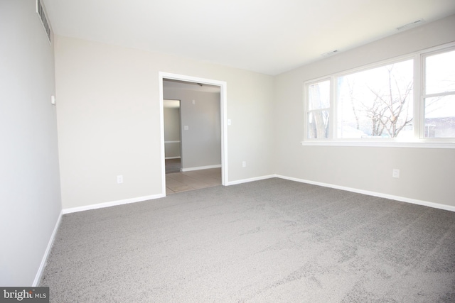 carpeted spare room with visible vents and baseboards