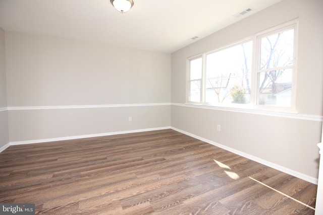 empty room featuring baseboards, visible vents, and dark wood finished floors