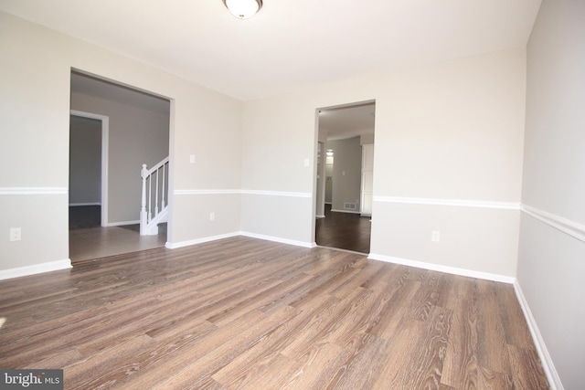 unfurnished room featuring baseboards, stairway, and wood finished floors