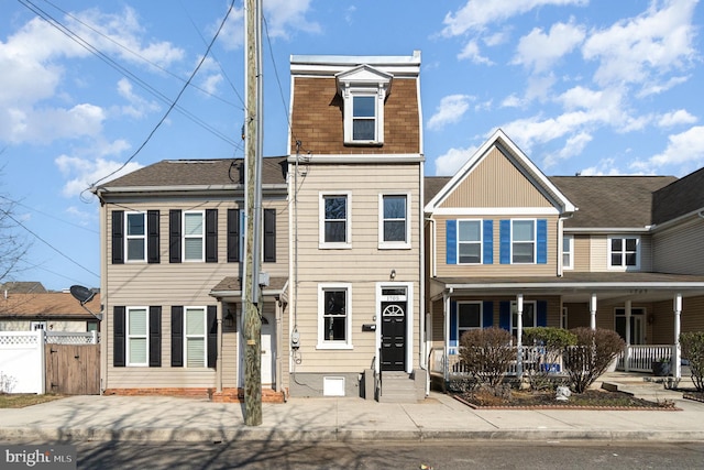 townhome / multi-family property with a shingled roof, fence, and a porch