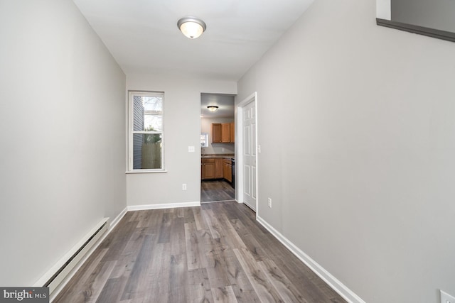 interior space featuring baseboards, a baseboard heating unit, and dark wood-style flooring