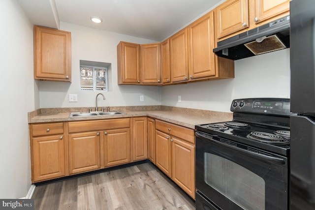 kitchen with under cabinet range hood, a sink, light countertops, black appliances, and light wood finished floors