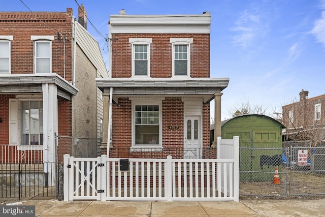 view of front of property with a fenced front yard, covered porch, brick siding, and a gate