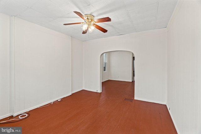 spare room with arched walkways, visible vents, a ceiling fan, wood finished floors, and baseboards