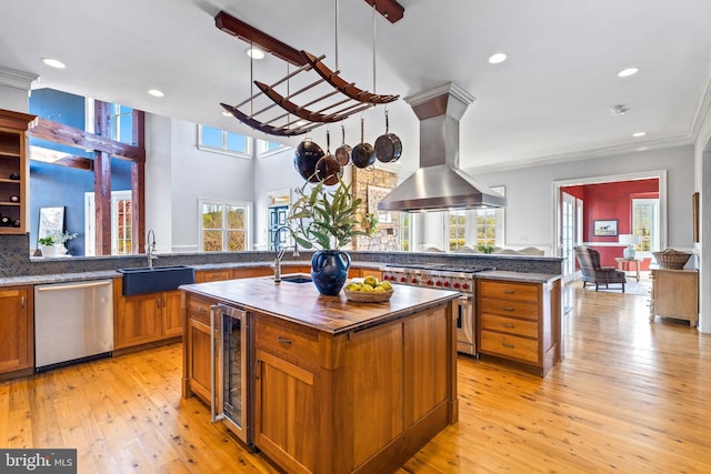 kitchen featuring beverage cooler, island exhaust hood, light wood finished floors, a sink, and appliances with stainless steel finishes