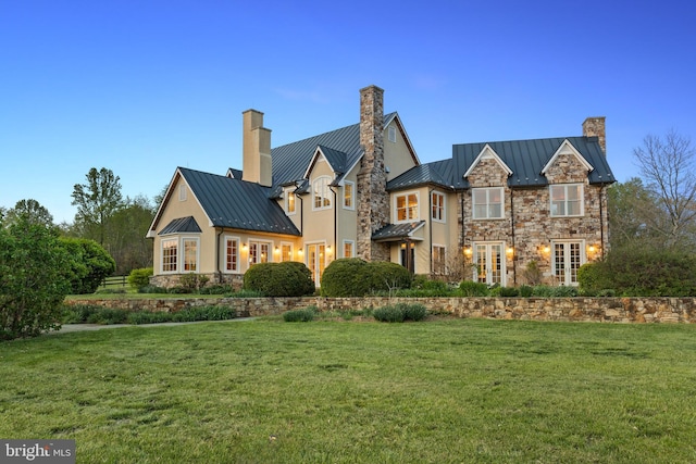 view of front facade with a chimney, a standing seam roof, stone siding, and metal roof