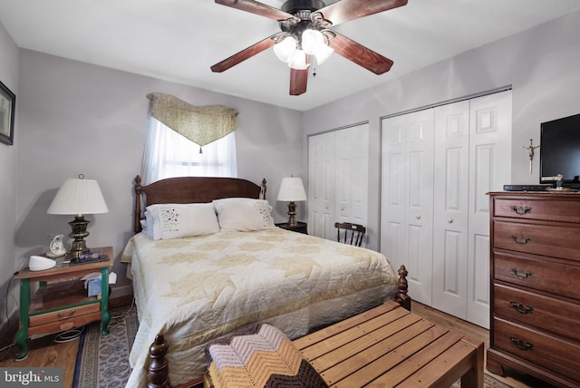 bedroom with two closets, a ceiling fan, and wood finished floors