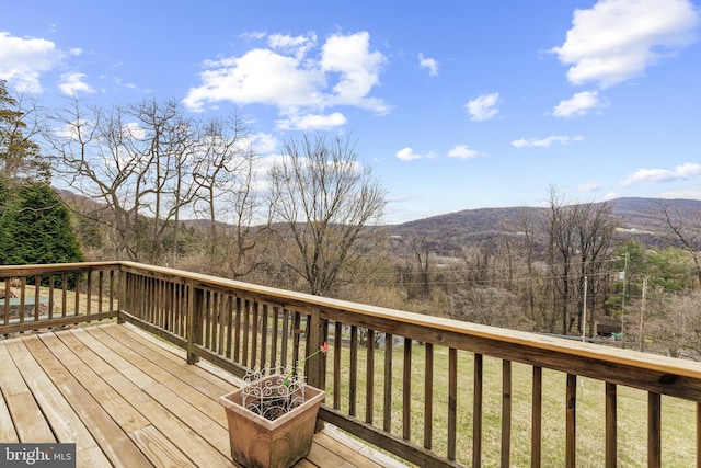 deck featuring a mountain view and a lawn