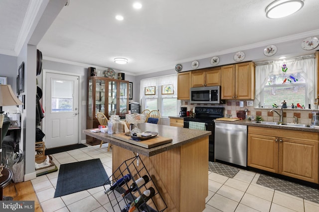 kitchen featuring light tile patterned floors, ornamental molding, a sink, appliances with stainless steel finishes, and tasteful backsplash