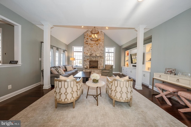 living area with ornate columns, dark wood-style floors, and a stone fireplace