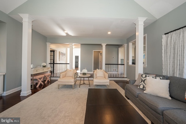 living room featuring baseboards, ornate columns, and wood finished floors