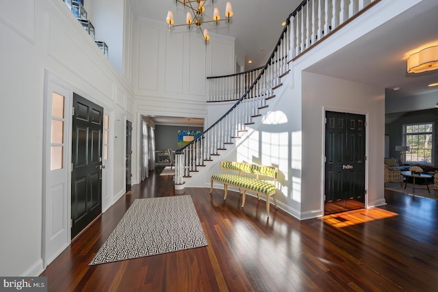 entryway with a high ceiling, wood-type flooring, stairs, and a chandelier