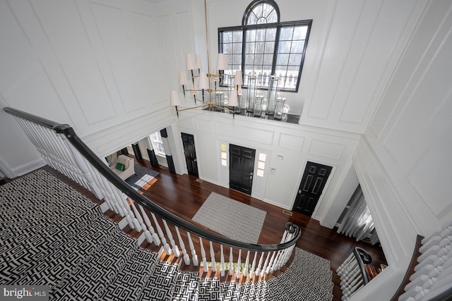 foyer featuring stairway, a decorative wall, and wood finished floors