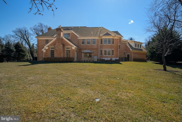 view of front of home with brick siding, a chimney, and a front lawn