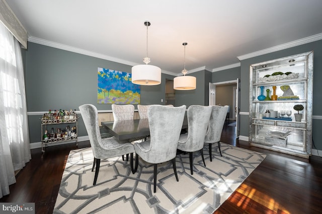 dining room featuring crown molding, baseboards, and wood finished floors