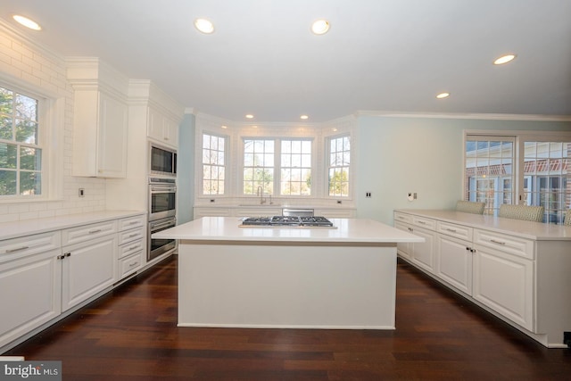 kitchen with decorative backsplash, a kitchen island, dark wood-style flooring, stainless steel appliances, and a sink