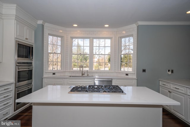 kitchen with crown molding, stainless steel appliances, light countertops, a sink, and plenty of natural light