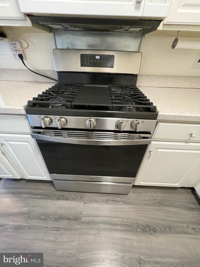 kitchen with white cabinets, stainless steel gas stove, and decorative backsplash