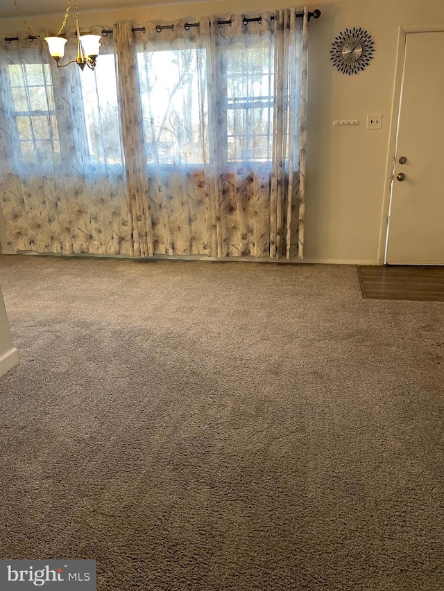 unfurnished dining area featuring a chandelier and carpet