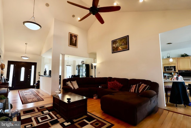 living room with light wood finished floors, high vaulted ceiling, ornate columns, and a ceiling fan