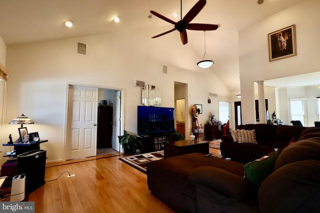 living room featuring visible vents, ceiling fan, decorative columns, light wood-style floors, and high vaulted ceiling