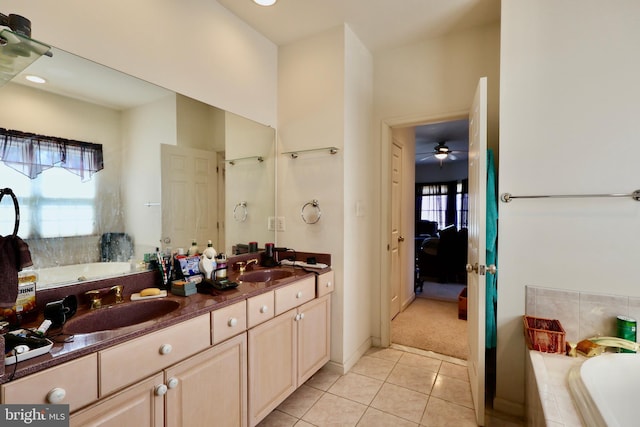 ensuite bathroom featuring tile patterned floors, a relaxing tiled tub, double vanity, and a sink