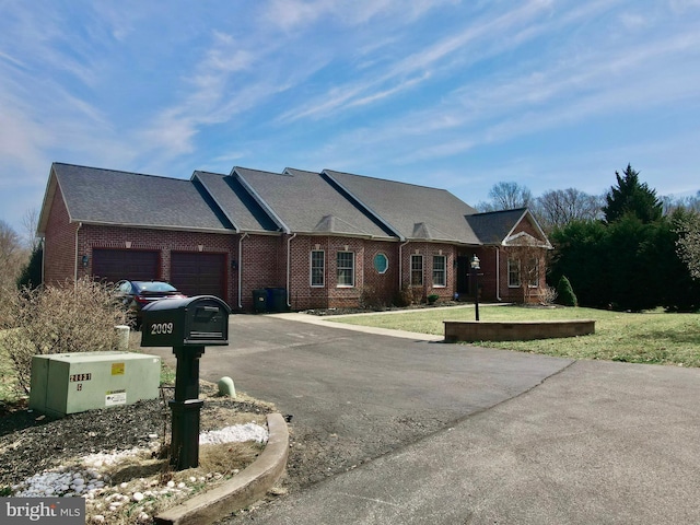 view of front of house with aphalt driveway, a front yard, brick siding, and an attached garage