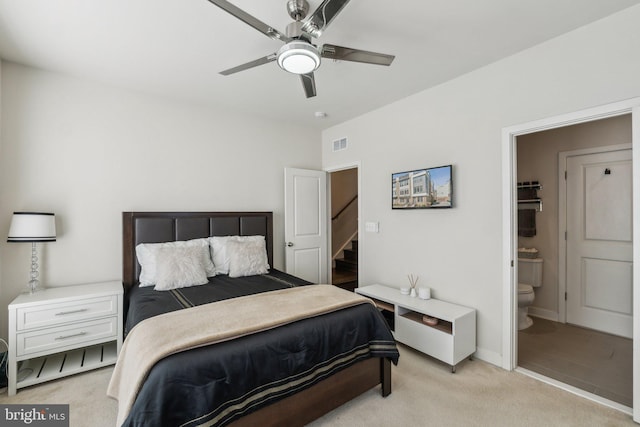 bedroom featuring visible vents, ensuite bathroom, baseboards, light colored carpet, and ceiling fan