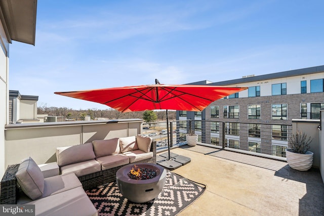 view of patio / terrace with an outdoor living space with a fire pit and a balcony