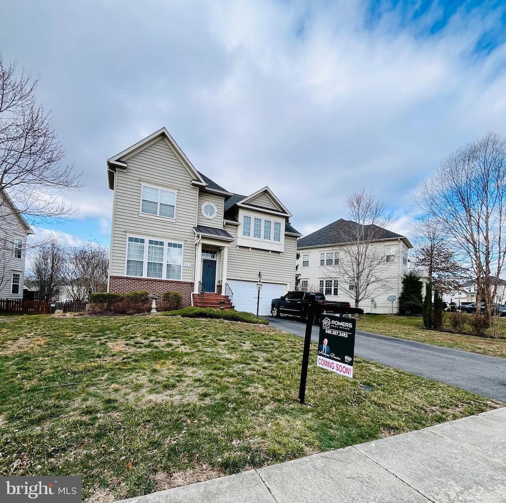 traditional-style home featuring an attached garage, a front lawn, aphalt driveway, and brick siding