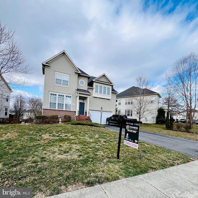 traditional-style home featuring an attached garage, a front lawn, aphalt driveway, and brick siding