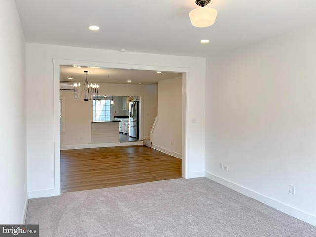 empty room featuring baseboards, an inviting chandelier, carpet flooring, and recessed lighting