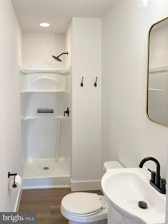 bathroom with toilet, baseboards, a walk in shower, and wood finished floors