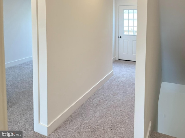 hallway featuring carpet and baseboards