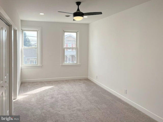 carpeted empty room featuring a wealth of natural light, ceiling fan, and baseboards