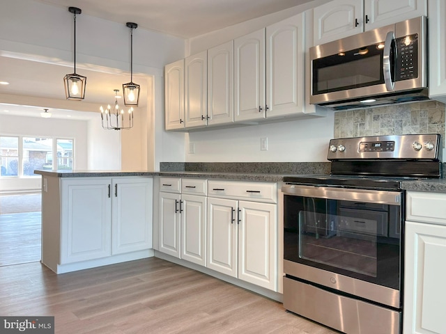 kitchen featuring stainless steel appliances, a peninsula, light wood-style flooring, and white cabinets