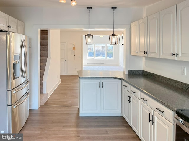 kitchen featuring light wood finished floors, stainless steel appliances, dark countertops, white cabinets, and a peninsula