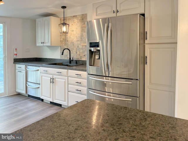 kitchen with dark countertops, appliances with stainless steel finishes, white cabinets, and a sink