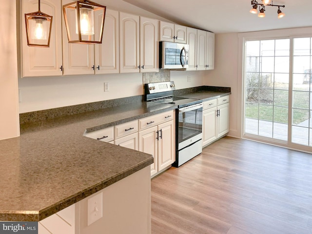 kitchen with dark countertops, light wood finished floors, white cabinets, and stainless steel appliances